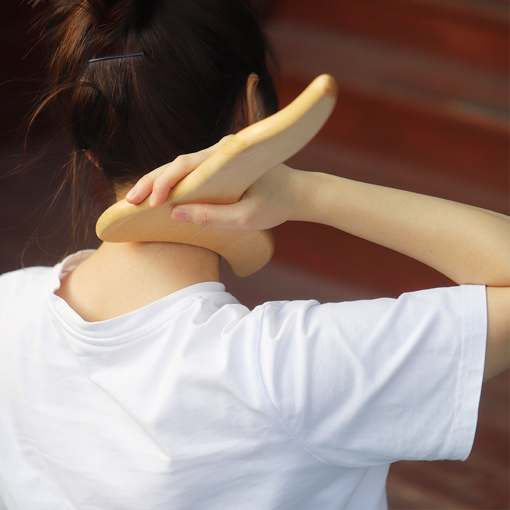 A person wearing a white shirt is using the Livingful Premium Wood Massage Tool 3 Sides on their neck for lymphatic drainage, with their hair tied back neatly.