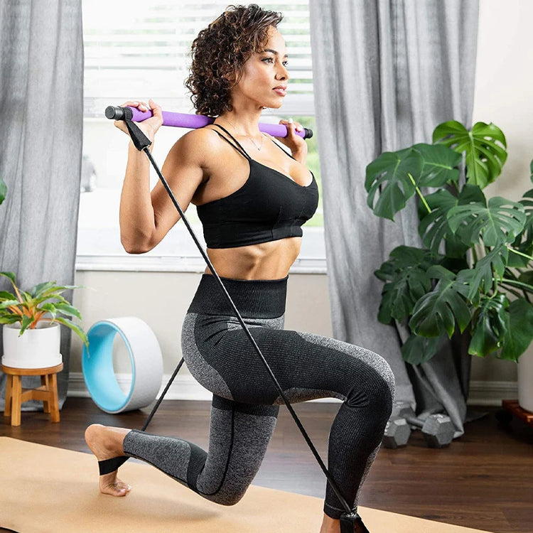 A woman is enhancing her lunges on a yoga mat by using the IPCBEC Multifunctional Pilates Bar and resistance bands for her workout. Her serene living room, adorned with lush plants and bathed in sunlight streaming through large windows, offers the perfect backdrop for her exercise routine.